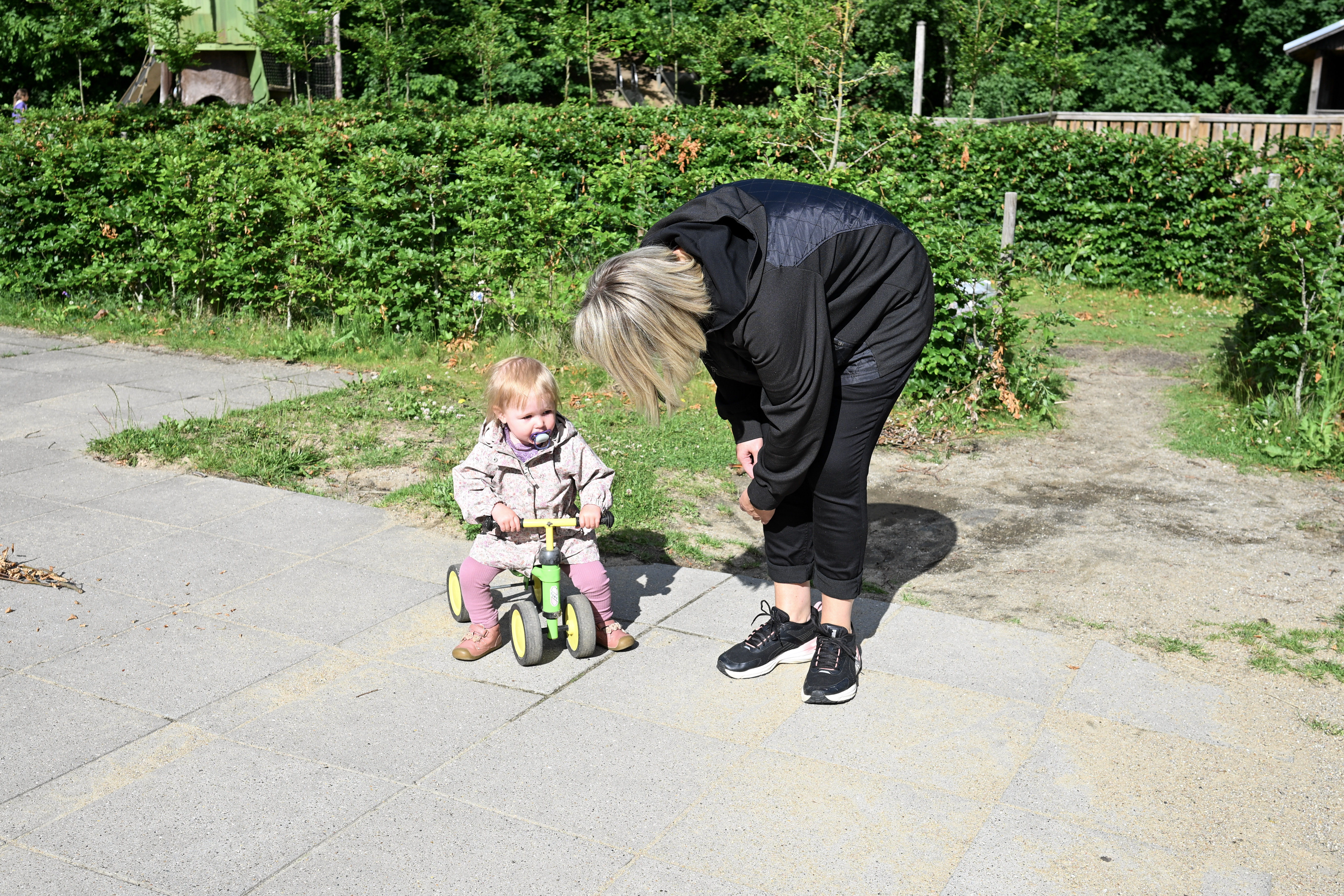 Voksen taler med barn på gåcykel