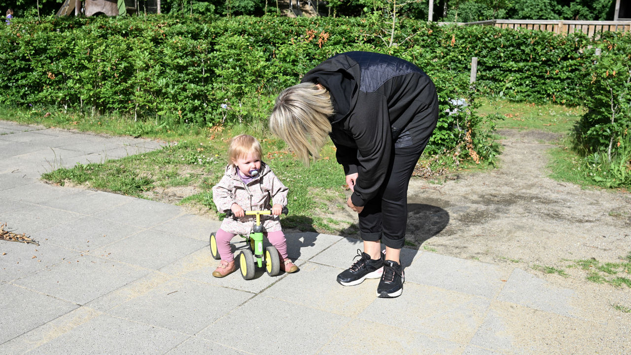 Voksen taler med barn på gåcykel