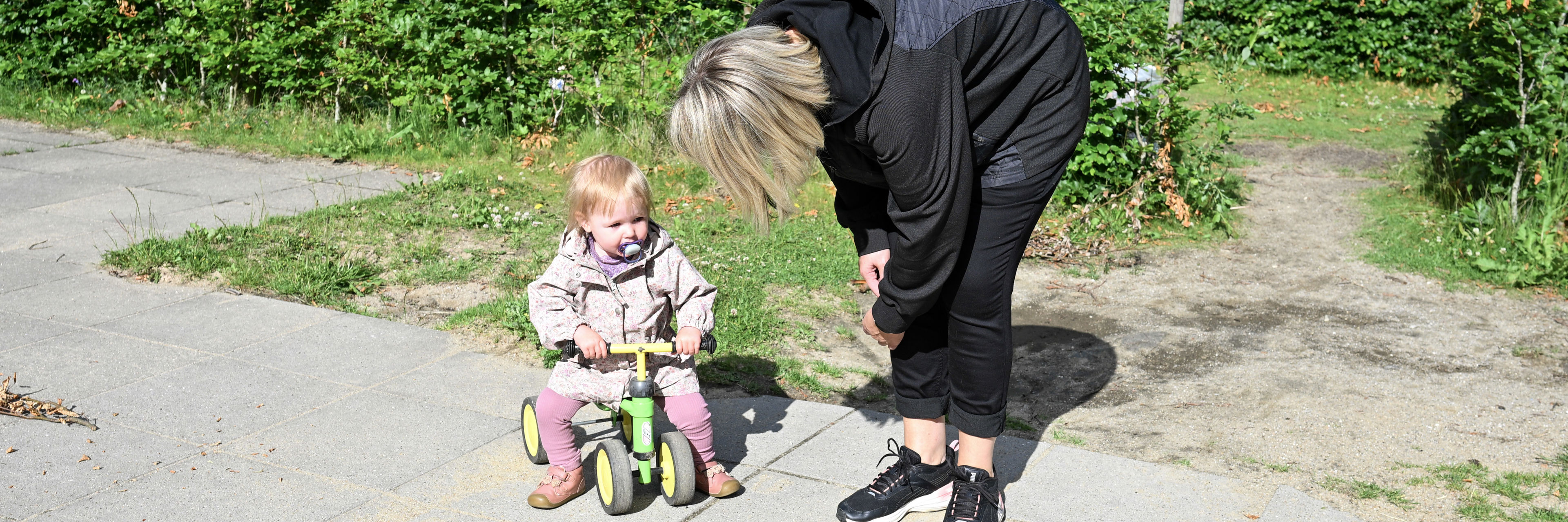 Voksen taler med barn på gåcykel