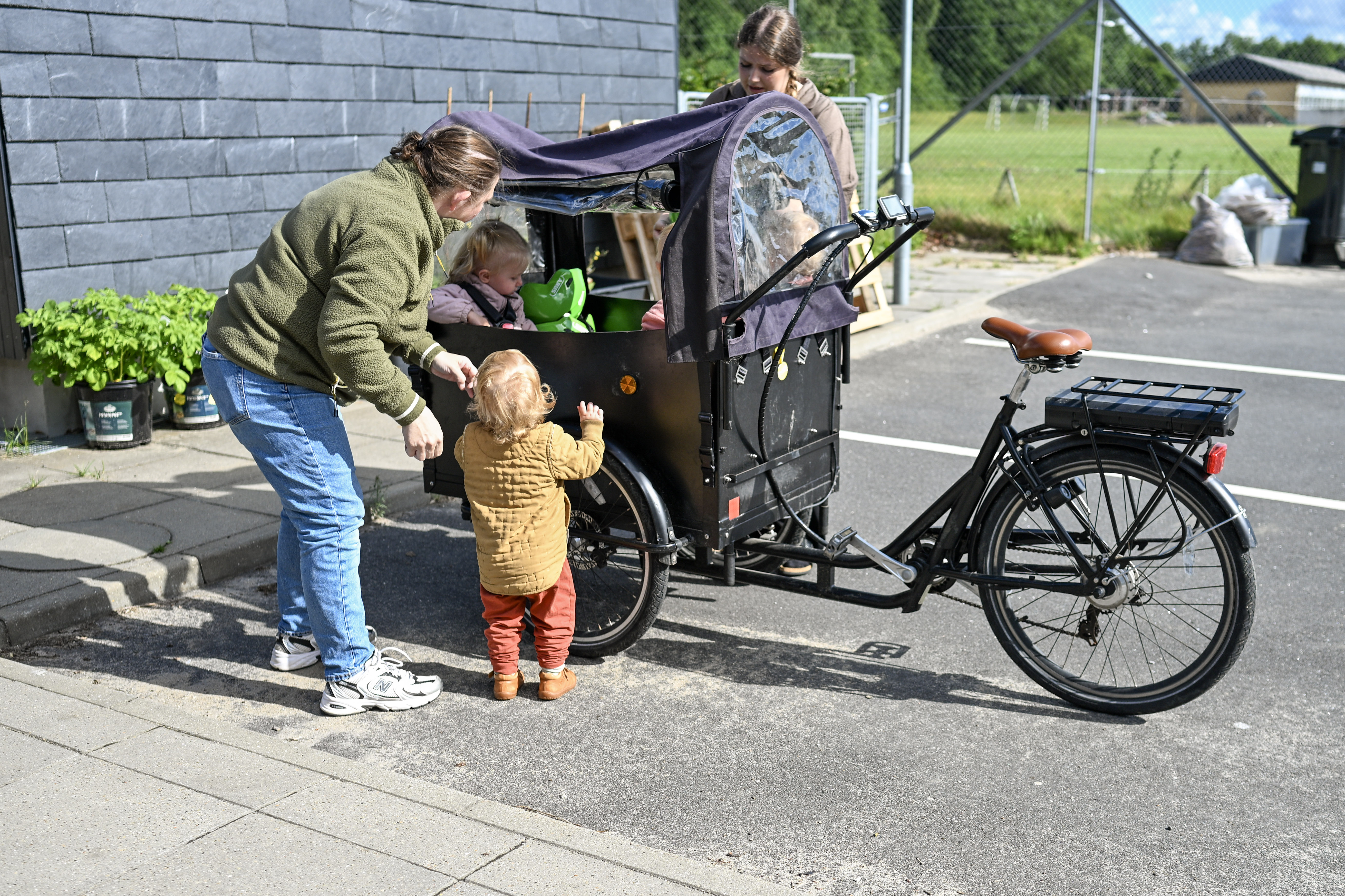 Voksne hjælper børn op i vognen på en ladcykel